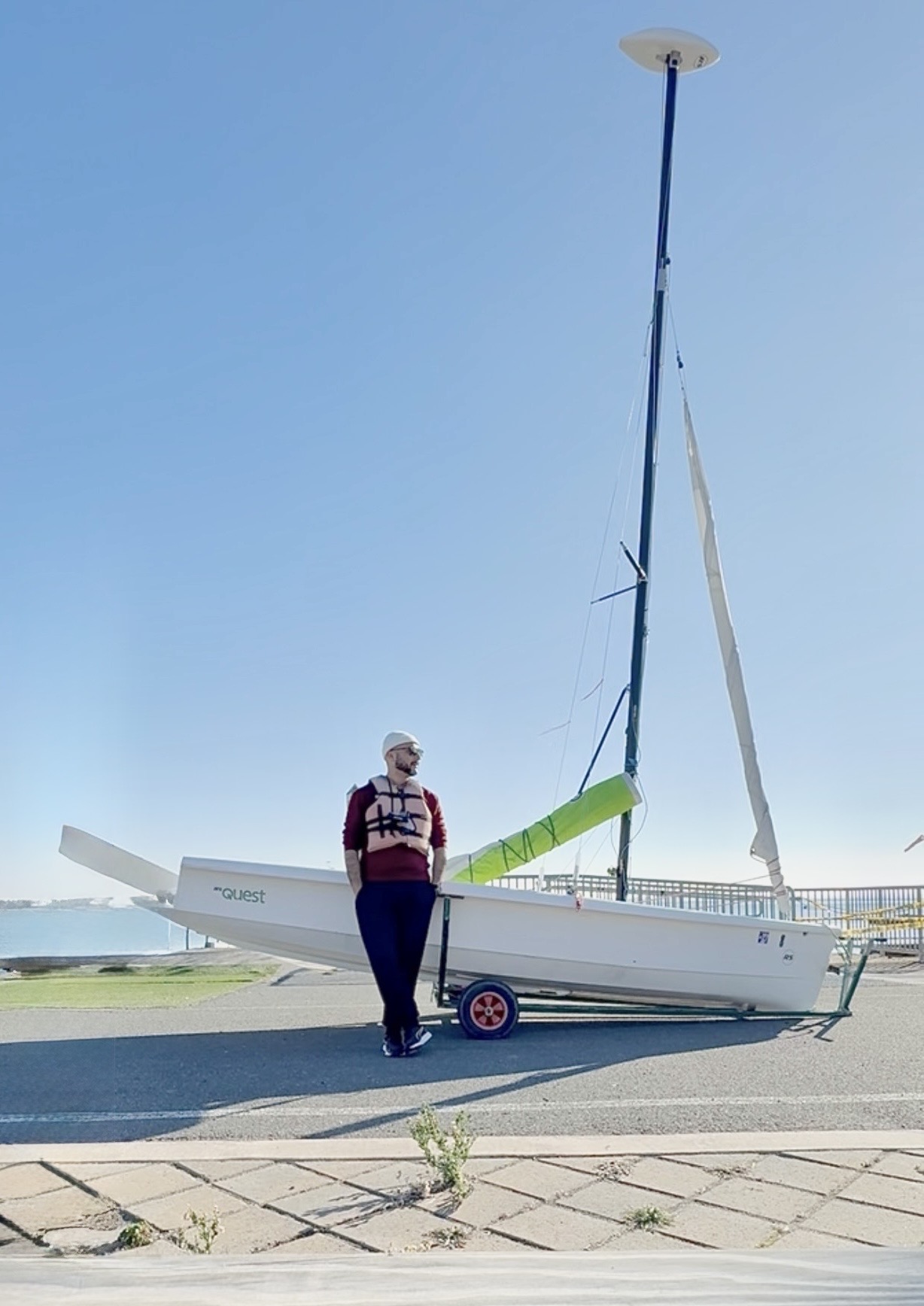 Christian standing beside a sailboat by the water.