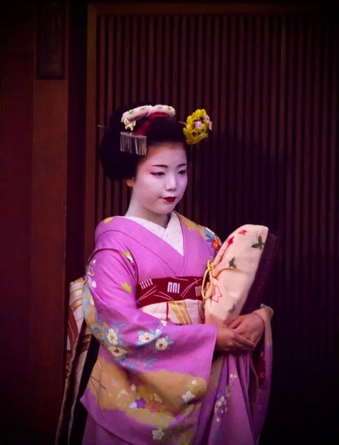 Person in a purple kimono standing in a dark doorway in Kyoto.