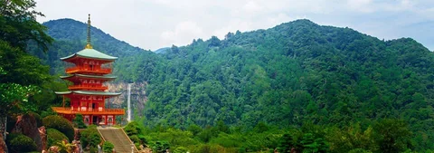 Red pagoda with a waterfall and green mountains at Nachi Falls.