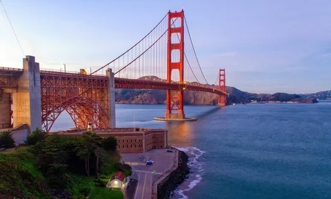 The Golden Gate Bridge at dusk, seen over the water from San Francisco.
