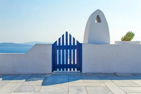 Blue gate and white building above the sea in Santorini.