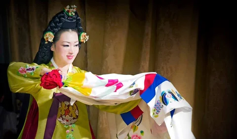Person in colorful traditional dress holding patterned fabric in Seoul.